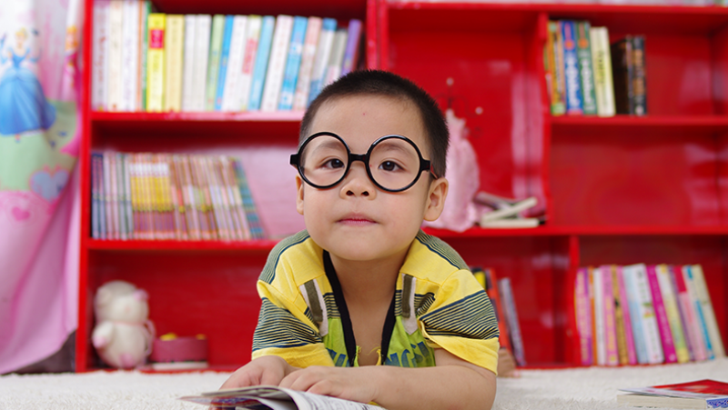 small boy in library reading a book