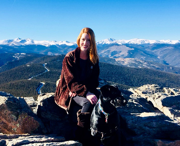 Caroline Malone Chaney on a mountain top with her dog