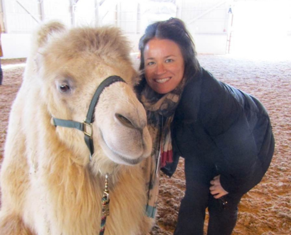 Betty Jean poses next to a camel in an indoor arena