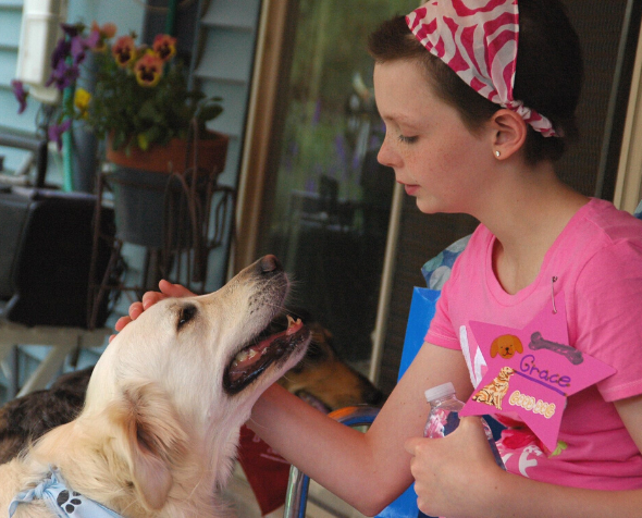 Young girl with a pink bandana and relaxed dog staring into each other's eyes.