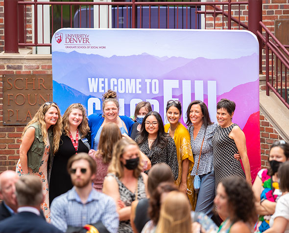 Group of people at an event posing for a photo in front of a backdrop reading Welcome to Wonderful Colorado
