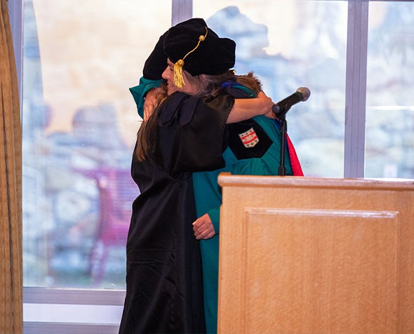 Associate Dean for Doctoral Education Jenn Greenfield hugs a PhD candidate in 2024 Phd Hooding Ceremony