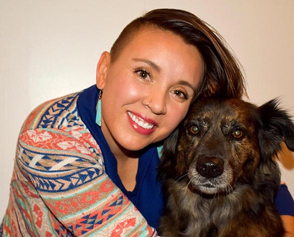 person with arms wrapped around black and grey dog 