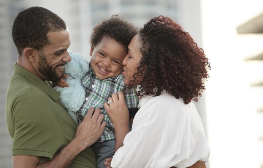 Man and woman holding and kissing child