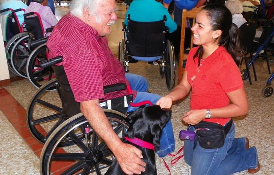 woman with therapy dog visiting man in wheelchair