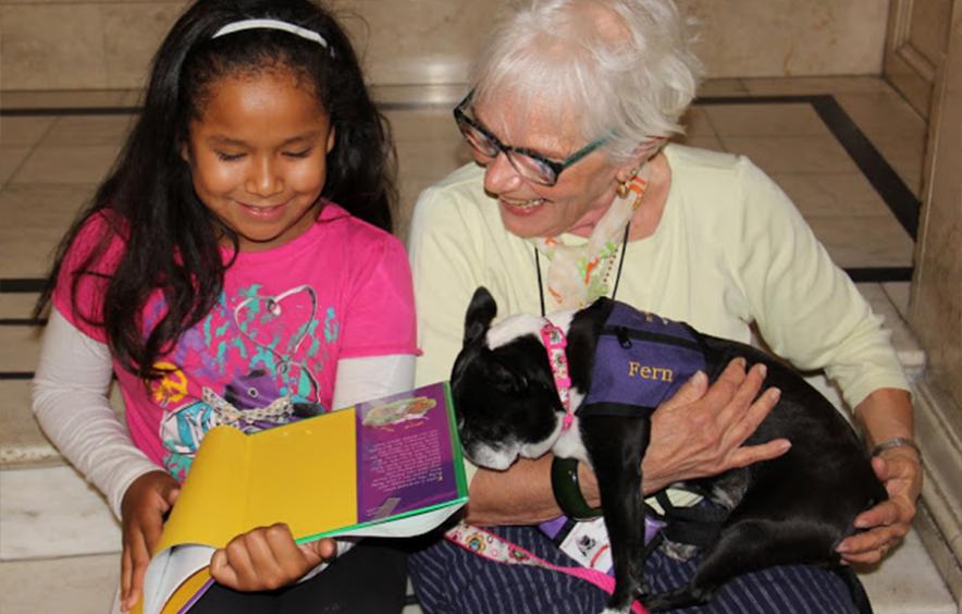 Young girl reading to therapy dog