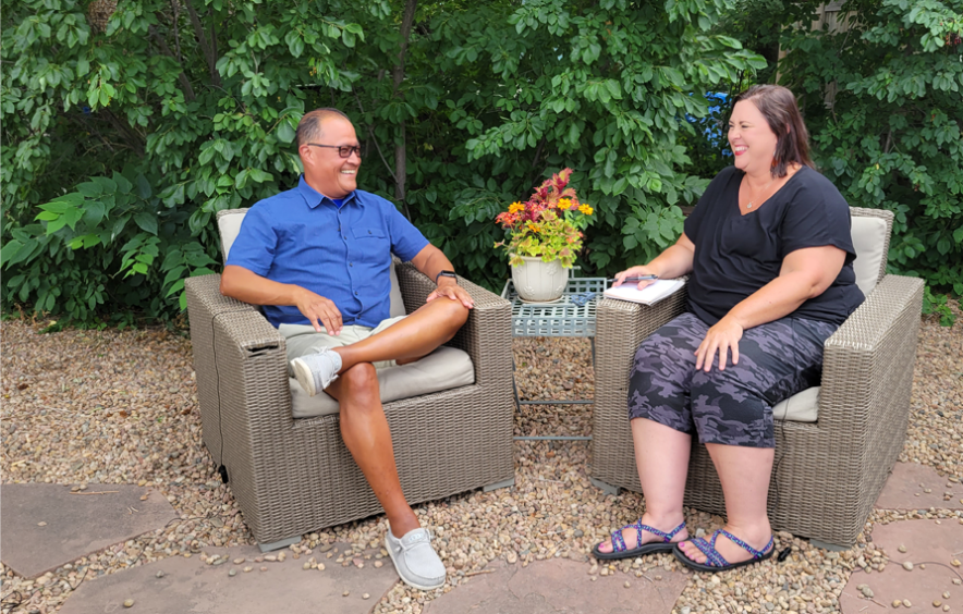 Man and Woman siting and smiling at each other while talking about coaching