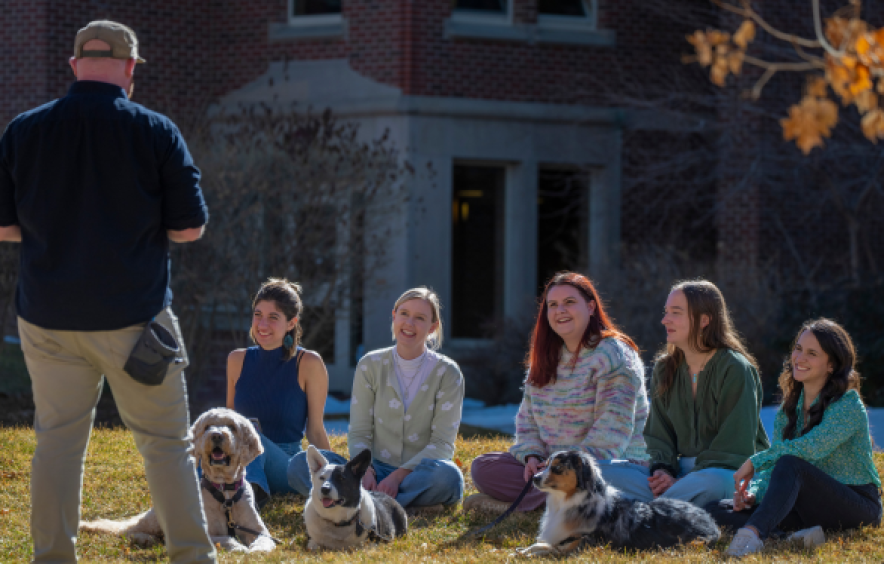 Students outside learning about dog-assisted therapy from expert instructor