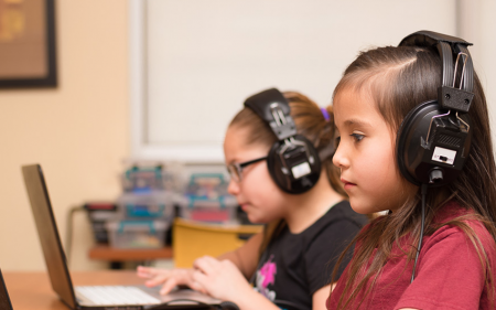 Two young students on laptops with headphones on