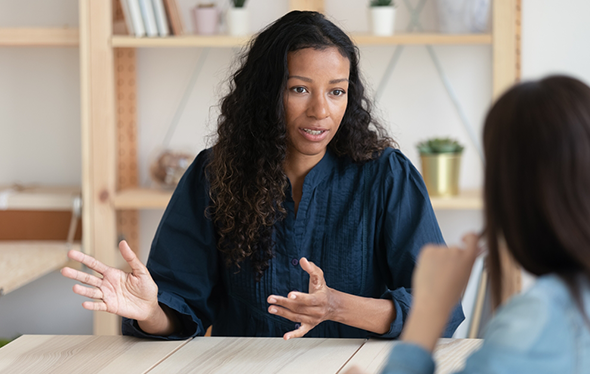 Female presenting person talking to another individual for coaching academy