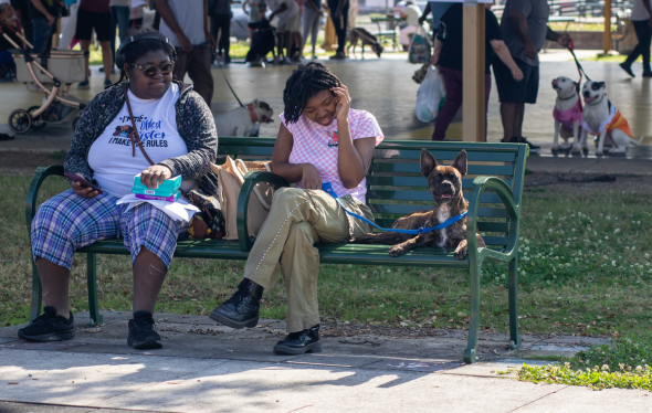Two people sitting on a bench with their dog at a community veterinary clinic