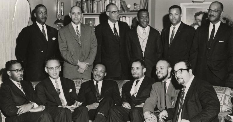 Greensboro, North Carolina, community members and John W. Mosley (back row, 4th from left) pose for a photo with Martin Luther King, Jr. (seated at center), after King’s speech at Bennet College in 1958. Source: Denver Public Library Special Collections
