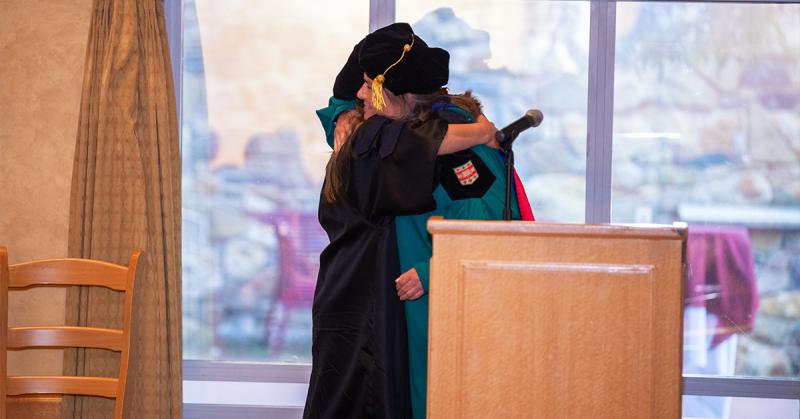 Associate Dean for Doctoral Education Jenn Greenfield hugs a PhD candidate in 2024 Phd Hooding Ceremony