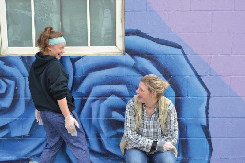 Mentor and Teen laughing in front of a mural