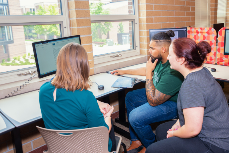 Small group of researchers gathered at a computer to analyze findings