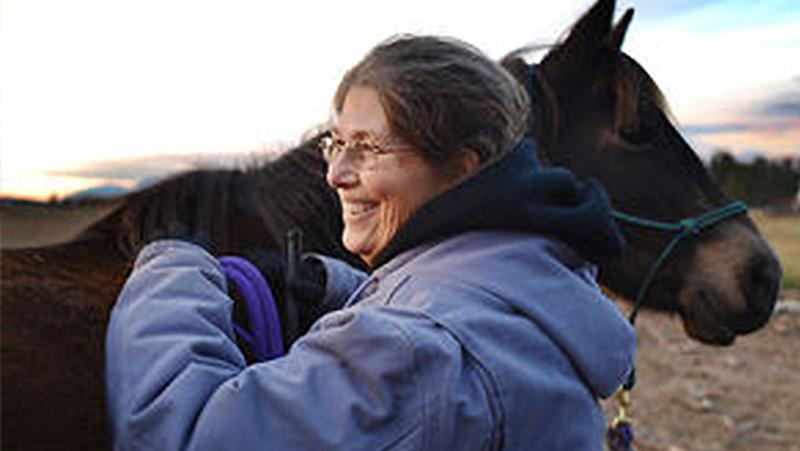 Woman standing next to horse.