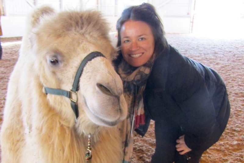 Betty Jean poses next to a camel in an indoor arena