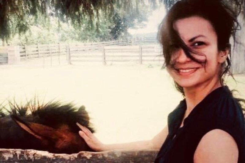 Mel Choubak standing outside petting a pony