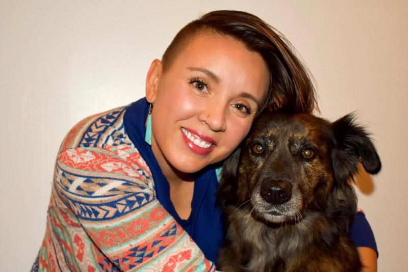 person with arms wrapped around black and grey dog